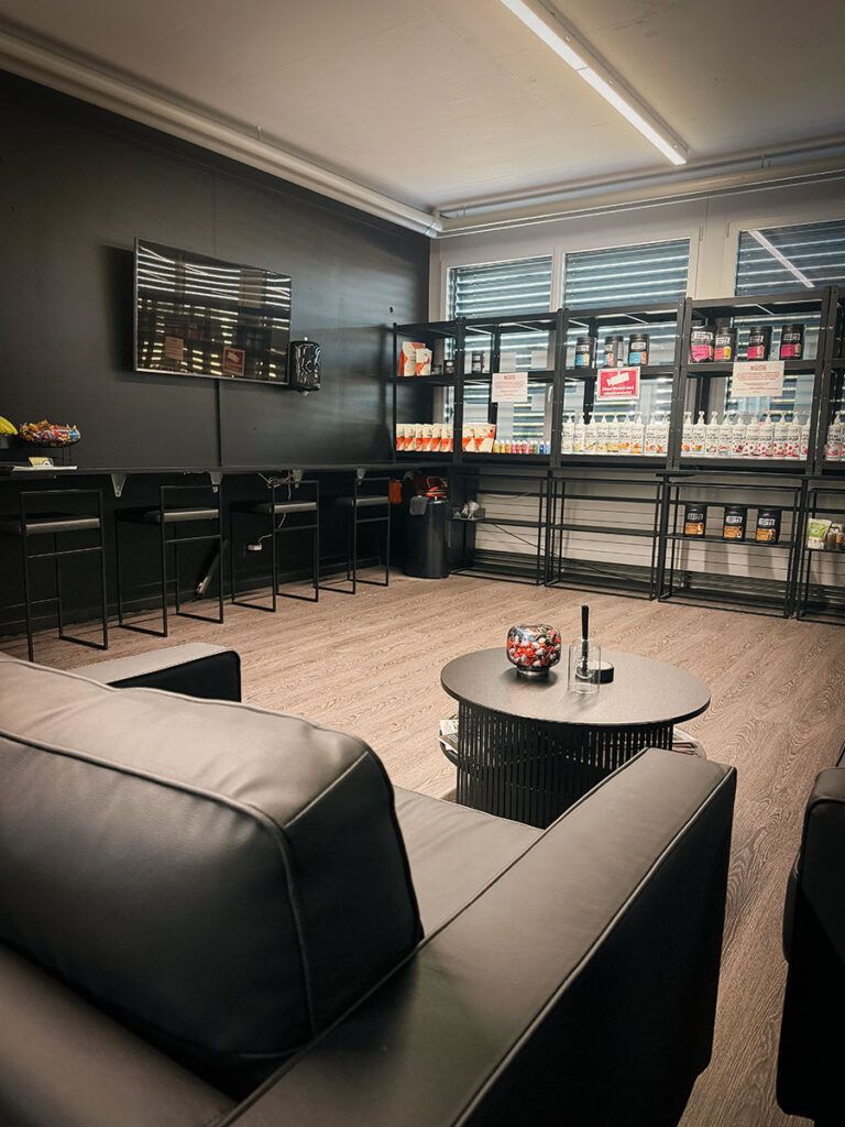 obsidian_gym_image00023 Loungebereich im OBSIDIAN Premium Fitness Studio in Sursee mit Sofas, TV und Regalen für Sportnahrung.