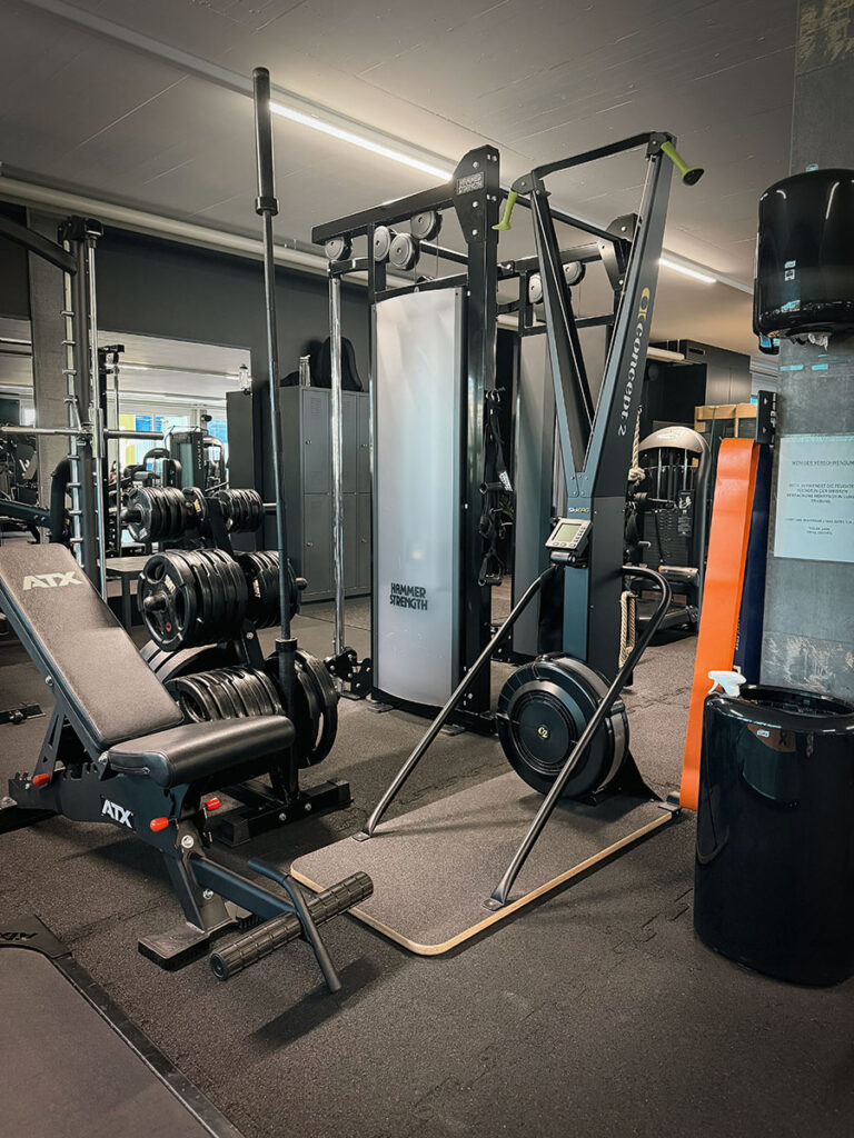 obsidian_gym_image00026 Trainingsbereich im OBSIDIAN Premium Fitness Studio in Sursee mit SkiErg, Trainingsbank, Gewichtsscheiben und Kraftstation.