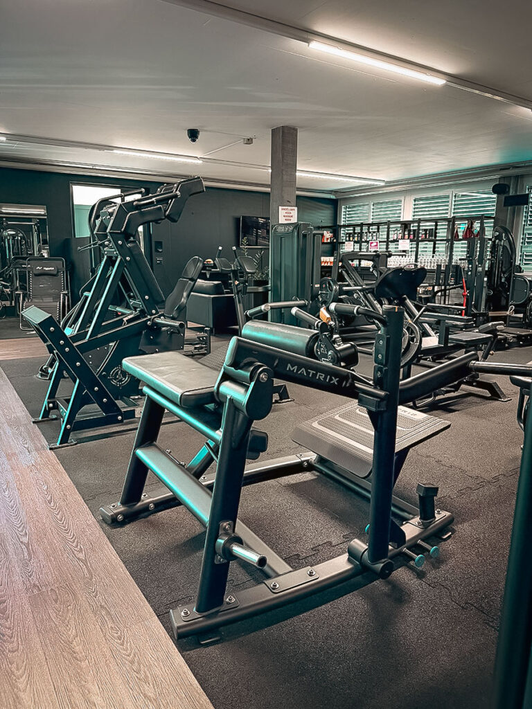 obsidian_gym_image00029_2 Gerätebereich im OBSIDIAN Premium Fitness Studio in Sursee mit Matrix-Kraftmaschine, Beinpresse und weiteren Trainingsstationen.