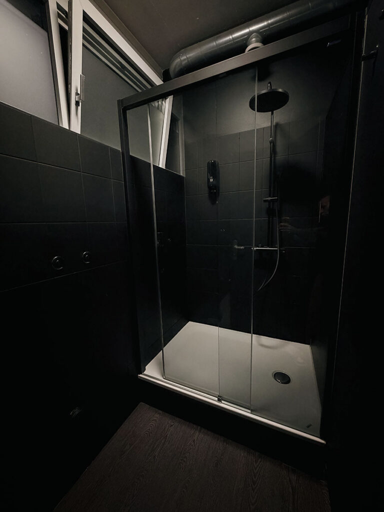 obsidian_gym_image00048 Duschbereich im OBSIDIAN Premium Fitness Studio in Sursee mit Glasdusche, Regendusche und schwarzer Armatur.